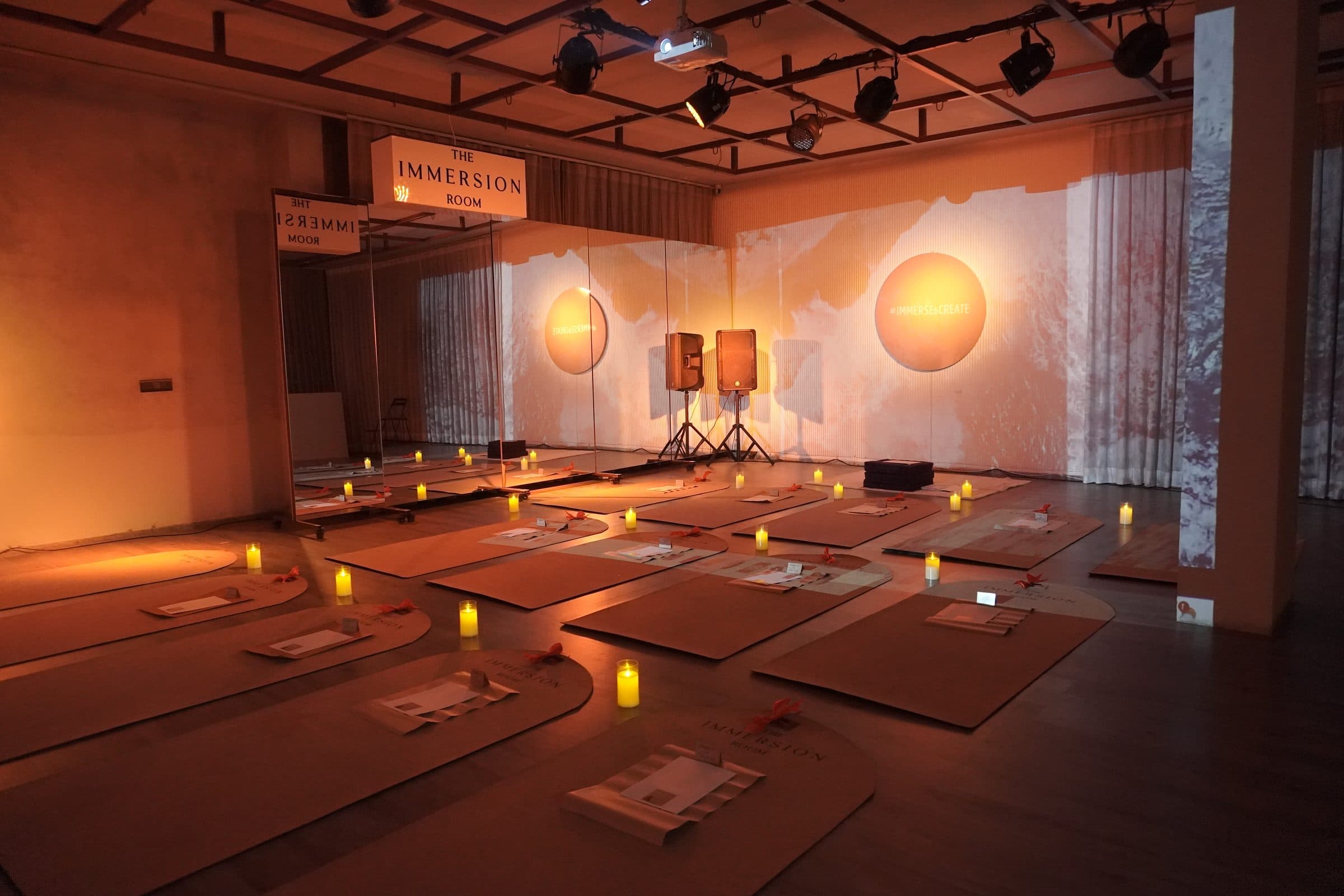The Immersion Room studio at golden hour, mats and candles laid out beneath a glowing disc
